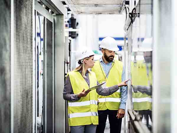 A portrait of an industrial man and woman engineer with tablet in a factory, working. Programmazione-plc-mantova